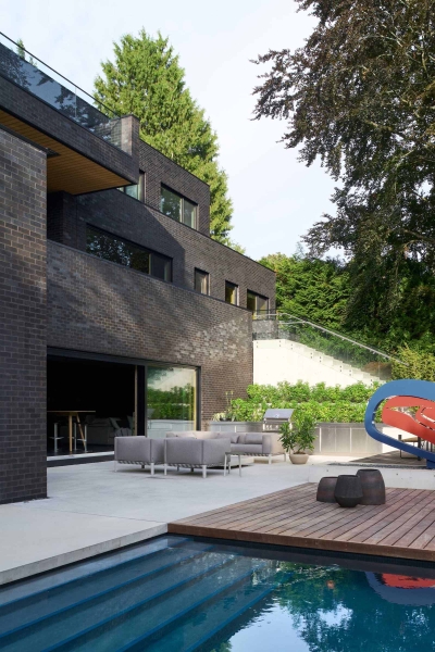 A Dark Brick Exterior For A Home Surrounded By Trees