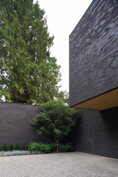 A Dark Brick Exterior For A Home Surrounded By Trees