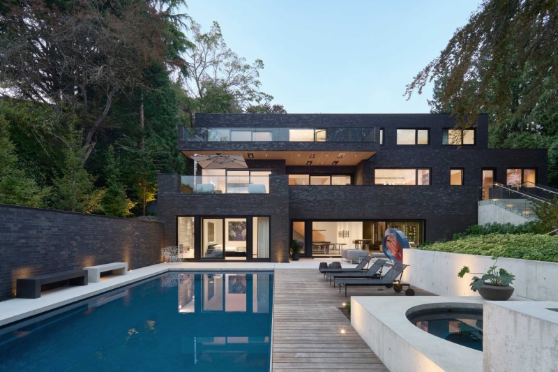 A Dark Brick Exterior For A Home Surrounded By Trees