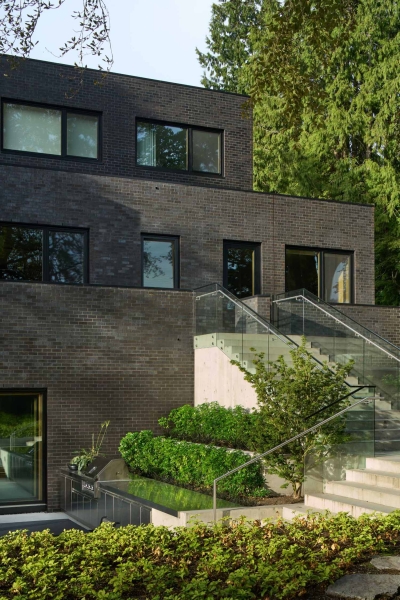 A Dark Brick Exterior For A Home Surrounded By Trees