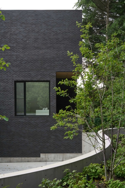 A Dark Brick Exterior For A Home Surrounded By Trees