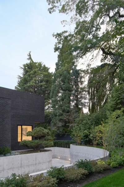 A Dark Brick Exterior For A Home Surrounded By Trees